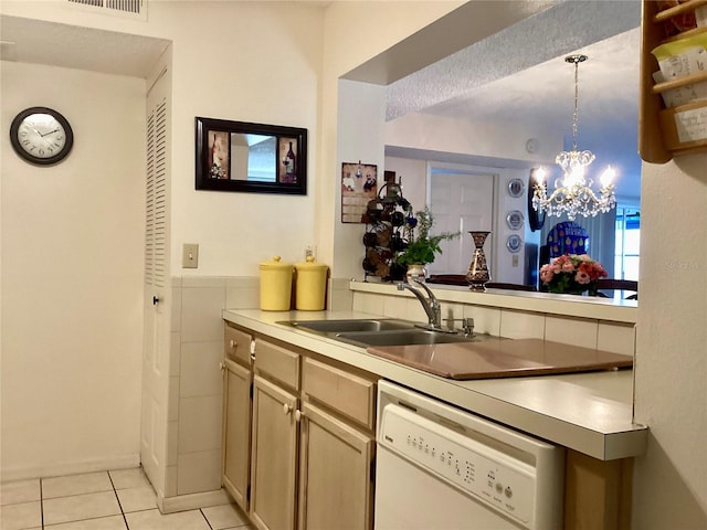 kitchen featuring light tile patterned flooring, dishwasher, a sink, pendant lighting, and a notable chandelier