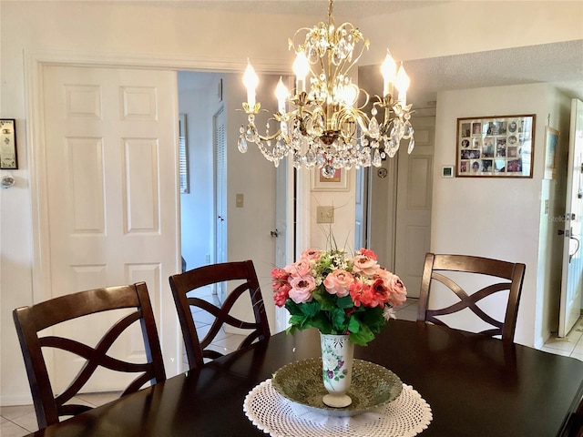 dining area with an inviting chandelier, tile patterned flooring, and a textured ceiling