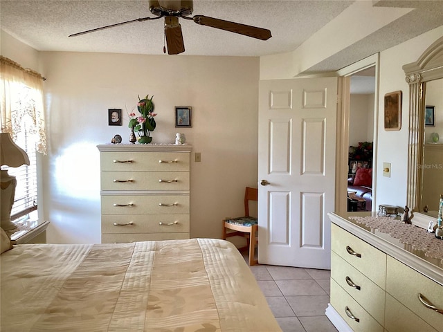 bedroom featuring a textured ceiling, a ceiling fan, and light tile patterned floors