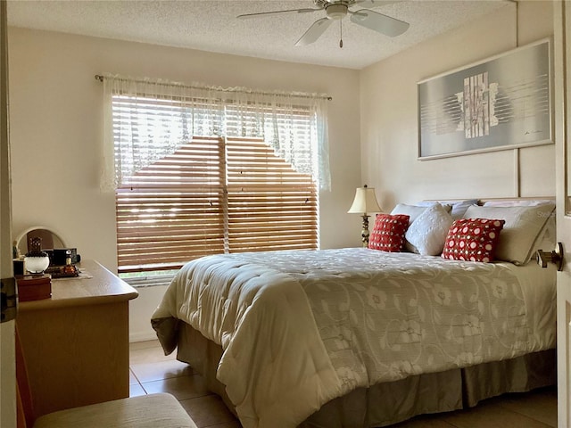 bedroom with a textured ceiling, ceiling fan, and light tile patterned floors