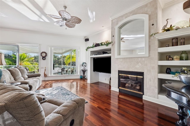 living room with dark wood-type flooring, ceiling fan, ornamental molding, and a fireplace