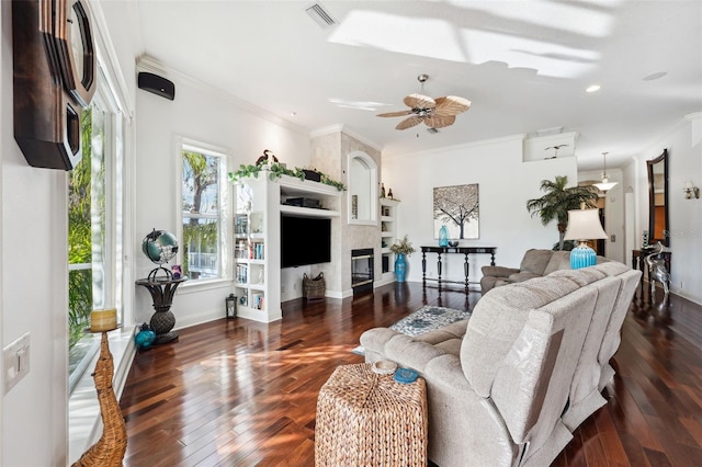 living room with ornamental molding, dark wood-type flooring, ceiling fan, and a fireplace