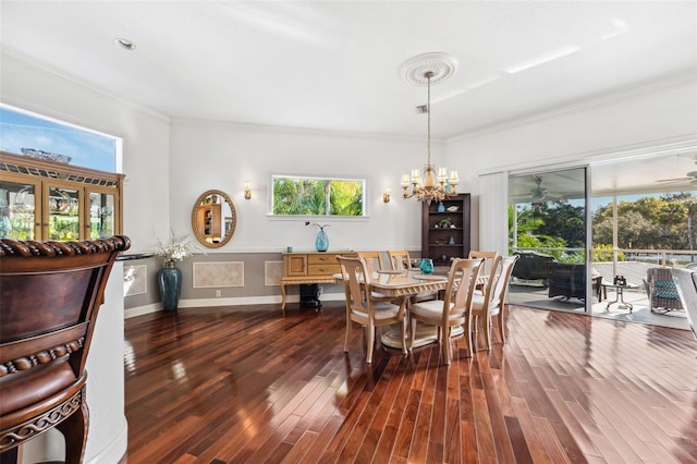 dining area with ornamental molding, dark hardwood / wood-style flooring, and ceiling fan with notable chandelier