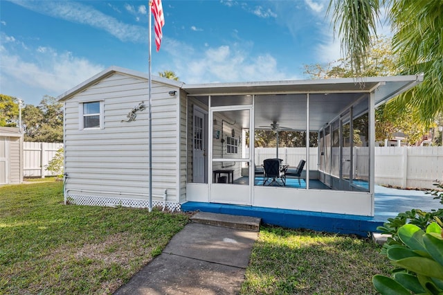 rear view of property featuring a lawn and a sunroom