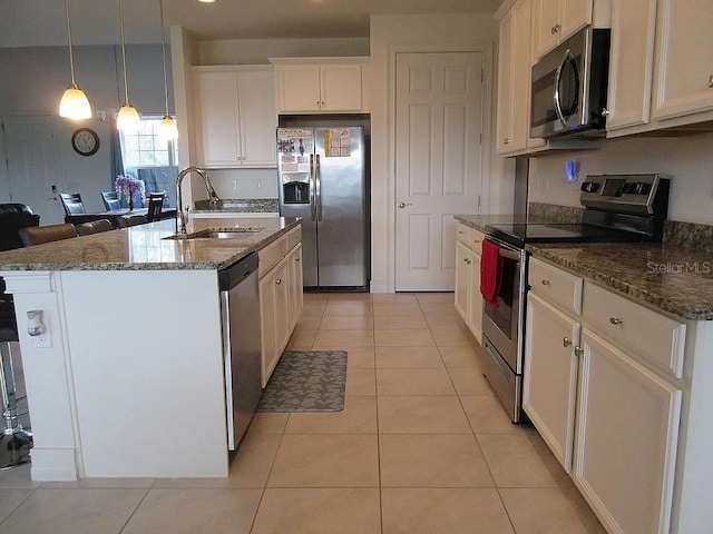 kitchen with sink, appliances with stainless steel finishes, white cabinetry, hanging light fixtures, and a center island with sink