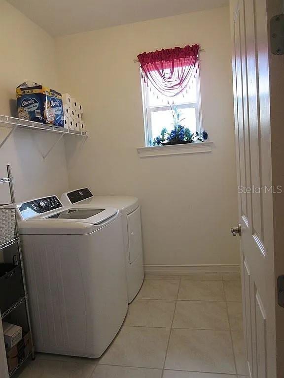 clothes washing area with independent washer and dryer and light tile patterned floors