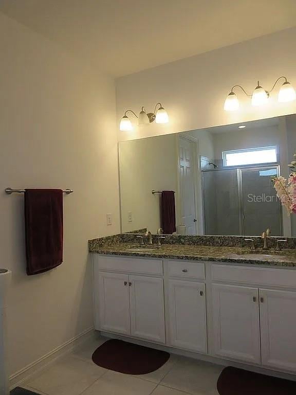 bathroom featuring a shower with door, vanity, and tile patterned floors