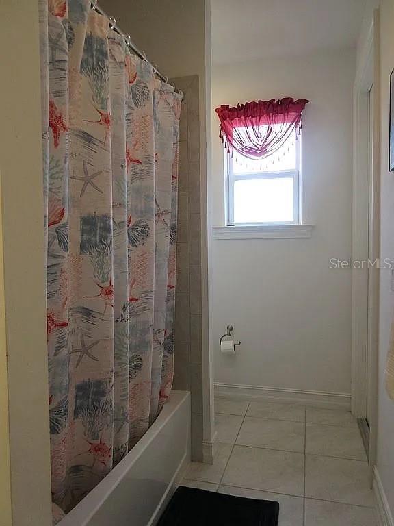 bathroom with shower / bath combination with curtain and tile patterned floors