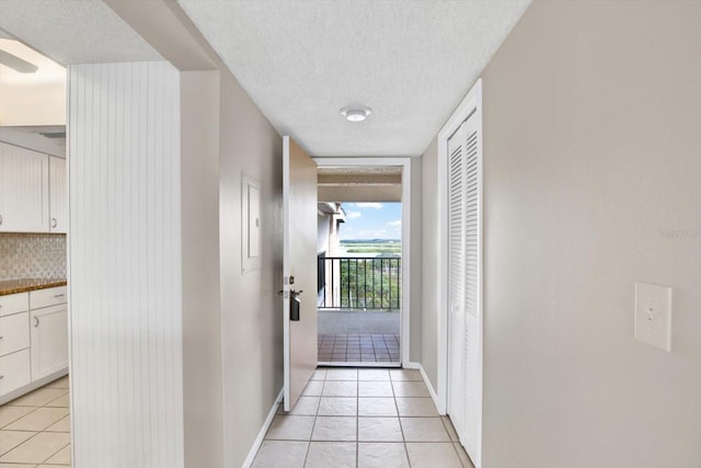 hall with expansive windows, light tile patterned floors, and a textured ceiling