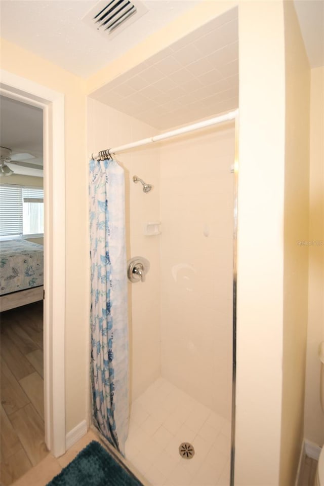 bathroom with hardwood / wood-style flooring, curtained shower, ceiling fan, and toilet