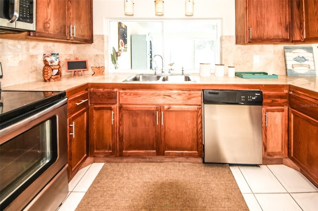 kitchen with appliances with stainless steel finishes, sink, light tile patterned floors, and backsplash