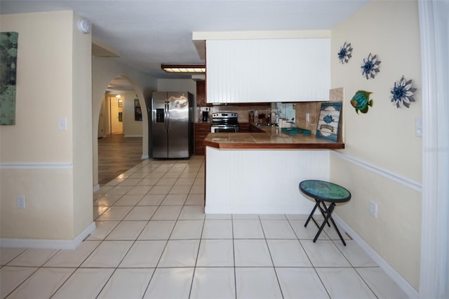 kitchen with tasteful backsplash, sink, light tile patterned floors, kitchen peninsula, and stainless steel appliances