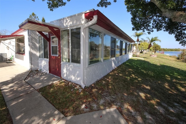 view of property exterior with a water view, cooling unit, and a lawn