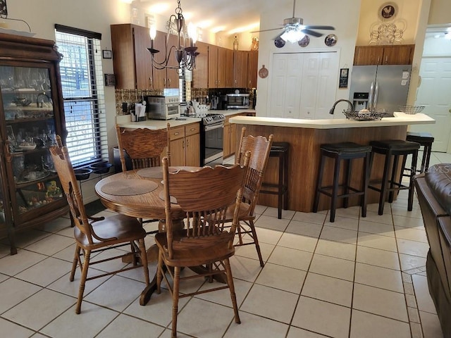 kitchen with light tile patterned floors, ceiling fan, backsplash, stainless steel appliances, and an island with sink