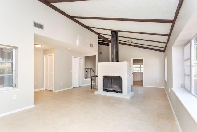 unfurnished living room with a brick fireplace, a textured ceiling, high vaulted ceiling, and beamed ceiling