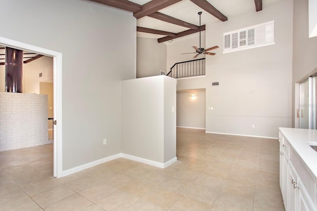 interior space featuring a high ceiling, beam ceiling, ceiling fan, and light tile patterned flooring