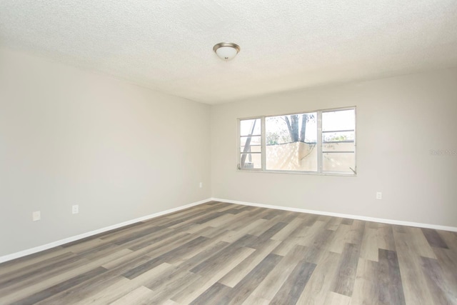 spare room featuring wood-type flooring and a textured ceiling