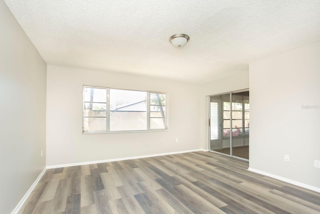 spare room featuring dark hardwood / wood-style floors and a textured ceiling