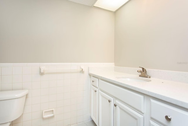 bathroom with vanity, tile walls, and toilet