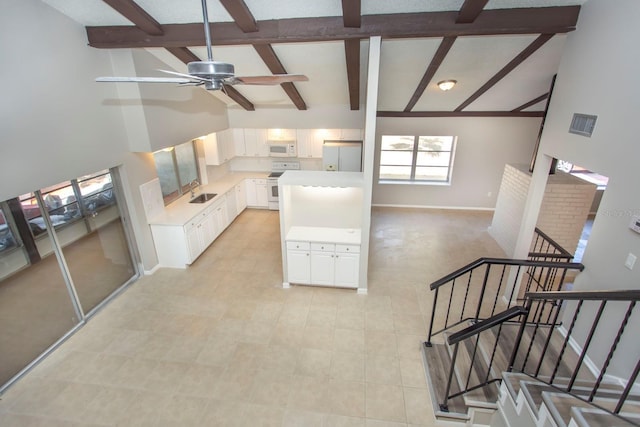 interior space featuring high vaulted ceiling, white cabinets, white appliances, ceiling fan, and beam ceiling