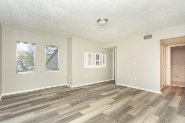 unfurnished room with wood-type flooring and a textured ceiling