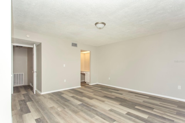 empty room featuring wood-type flooring and a textured ceiling