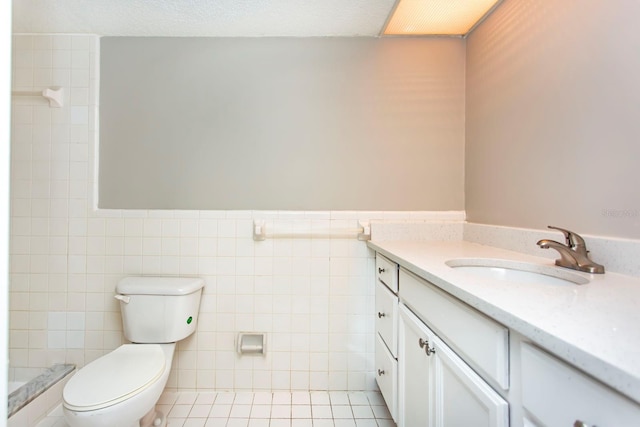 bathroom featuring tile patterned flooring, vanity, tile walls, and toilet