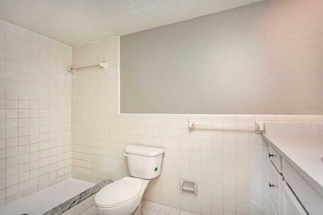 bathroom featuring vanity, tile walls, toilet, and a textured ceiling