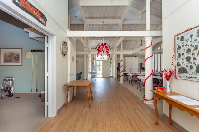 hallway with beam ceiling, decorative columns, and light wood-type flooring