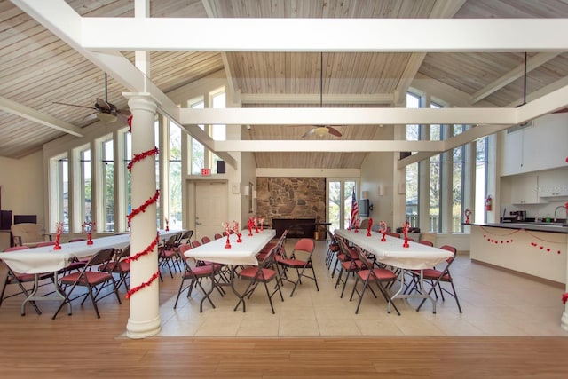 dining room with beamed ceiling, light tile patterned floors, a fireplace, and ceiling fan