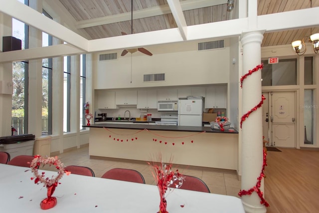 kitchen featuring beamed ceiling, high vaulted ceiling, light tile patterned floors, and white appliances