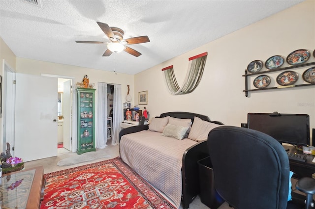 carpeted bedroom featuring ceiling fan and a textured ceiling