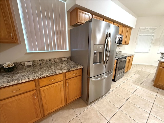 kitchen with light tile patterned flooring, appliances with stainless steel finishes, and stone counters