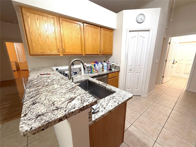 kitchen with light stone counters, kitchen peninsula, sink, and light tile patterned floors