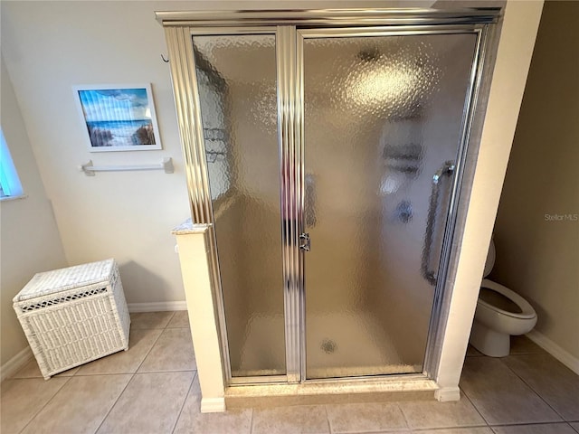 bathroom featuring a shower with door, tile patterned flooring, and toilet