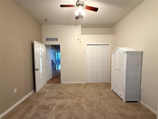 unfurnished bedroom featuring ceiling fan, a closet, a textured ceiling, and carpet