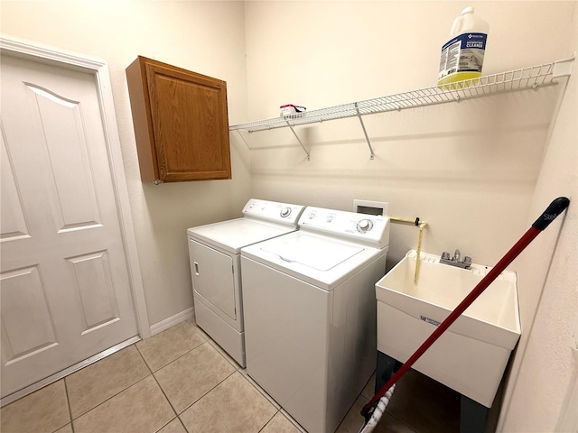 washroom featuring sink, light tile patterned floors, washer and clothes dryer, and cabinets