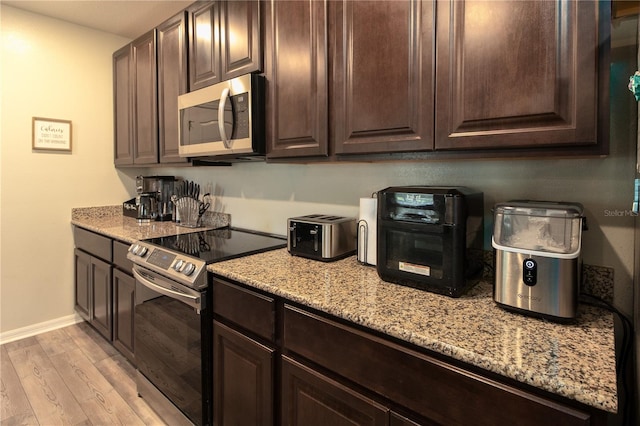 11134 Horned Owl Rd, Weeki Wachee, FL 34614 - kitchen with light wood-style flooring, baseboards, dark brown cabinetry, light stone countertops, and appliances with stainless steel finishes