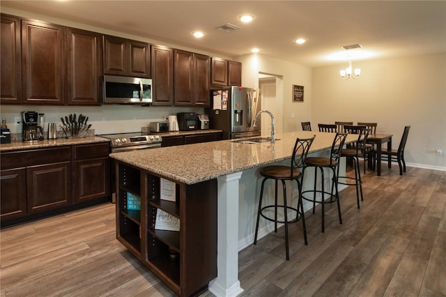 11134 Horned Owl Rd, Weeki Wachee, FL 34614 - kitchen featuring a kitchen breakfast bar, a sink, light wood-style floors, appliances with stainless steel finishes, and visible vents
