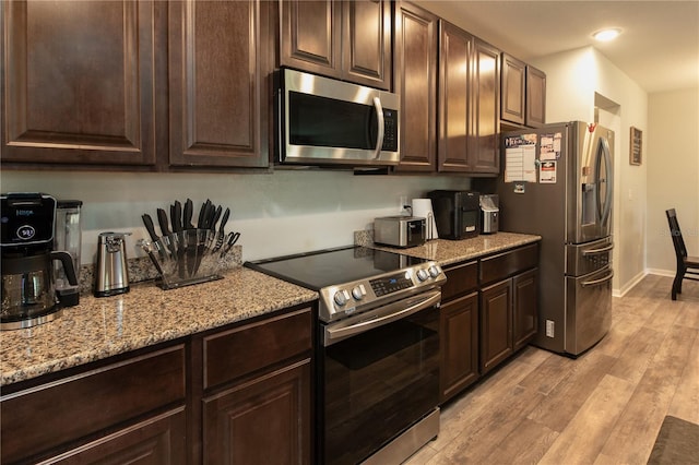 11134 Horned Owl Rd, Weeki Wachee, FL 34614 - kitchen with dark brown cabinets, light wood-style flooring, and stainless steel appliances