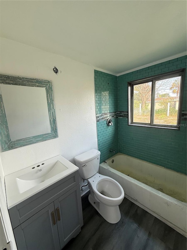 full bathroom featuring vanity, tiled shower / bath, wood-type flooring, and toilet