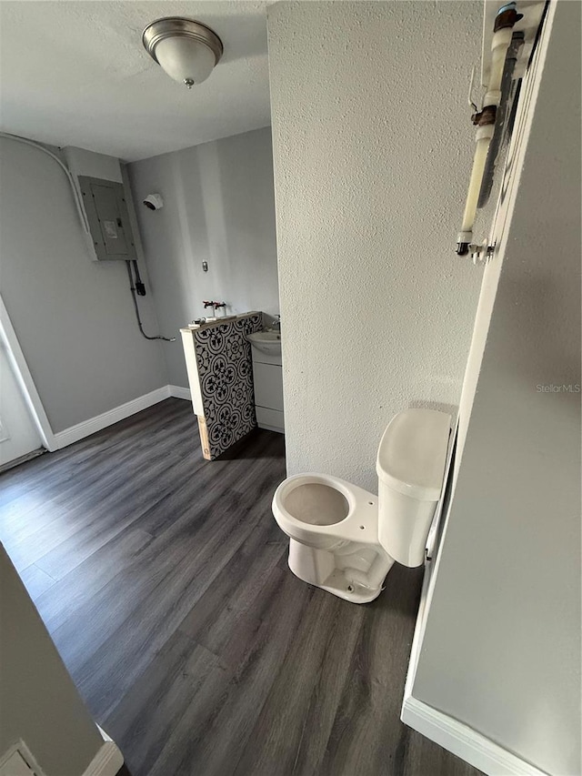 bathroom featuring hardwood / wood-style flooring, toilet, and electric panel