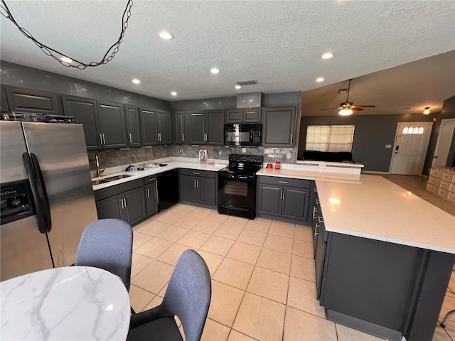 kitchen with a sink, black appliances, backsplash, and light countertops