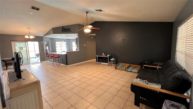 living area featuring lofted ceiling, visible vents, and light tile patterned floors