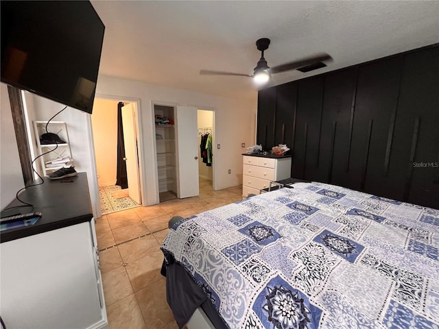 bedroom featuring light tile patterned floors, a textured ceiling, ceiling fan, a spacious closet, and a closet