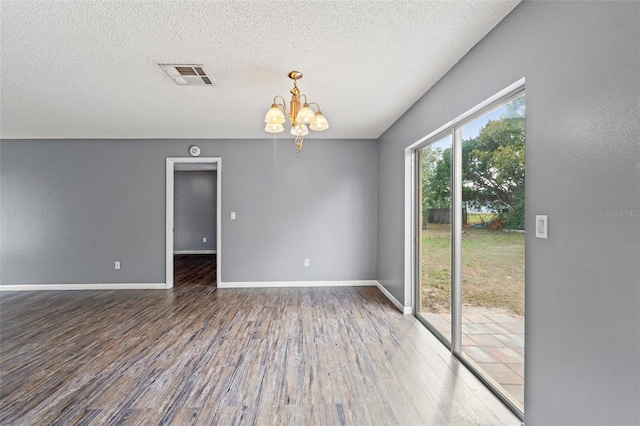 empty room featuring baseboards, visible vents, wood finished floors, an inviting chandelier, and a textured ceiling