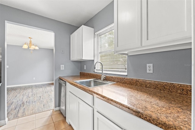 kitchen with a notable chandelier, stainless steel dishwasher, white cabinetry, a sink, and light tile patterned flooring