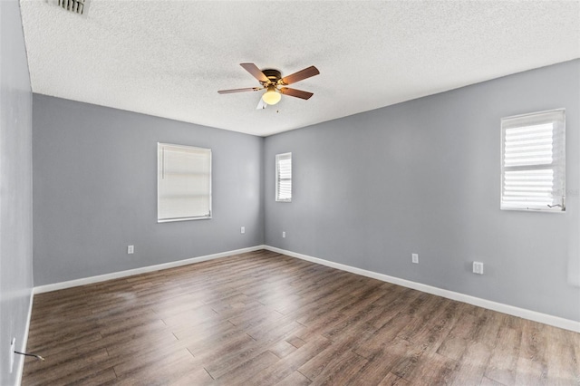 spare room with visible vents, ceiling fan, baseboards, and wood finished floors