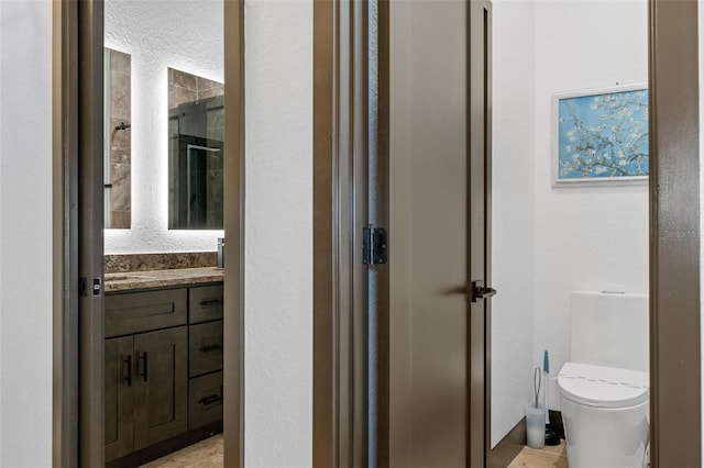 bathroom featuring vanity, an enclosed shower, and toilet