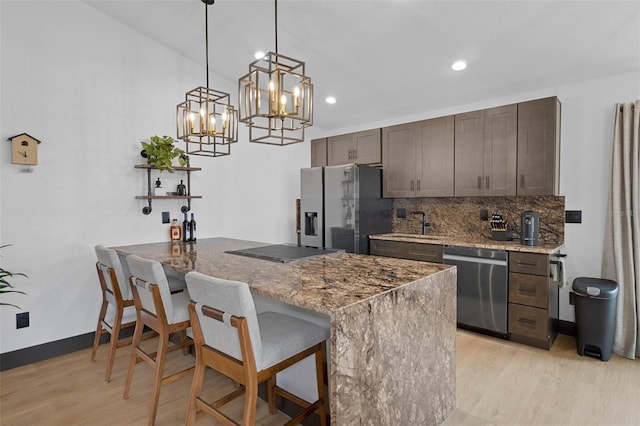10209 W Waterlander Loop Unit 164, Homosassa, FL 34448 - kitchen with stainless steel appliances, light wood finished floors, backsplash, a kitchen bar, and dark brown cabinetry